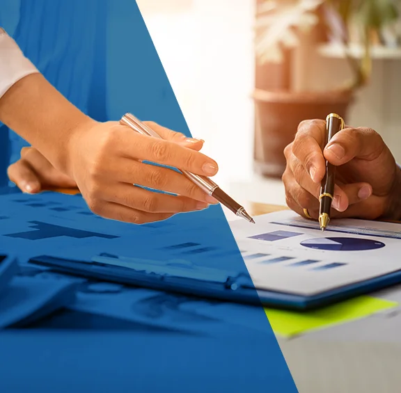 close up photo of a hand holding a pen pointing to charts on paper